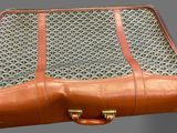 a brown suitcase that is hanging on the wall