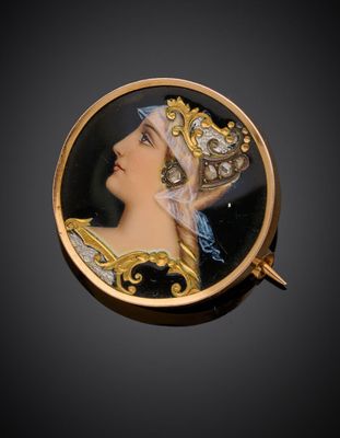 Une broche en or représente une femme portant un chapeau et une écharpe bleue.