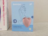 a pink heart shaped device sitting next to a box of toothpaste