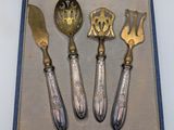 four pieces of silverware are in a case with a blue lining