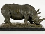 statue d'un rhinocéros posée sur un socle en marbre, sur fond blanc