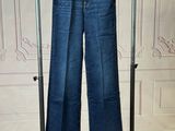 jeans hanging on a clothes rack in front of a white wall