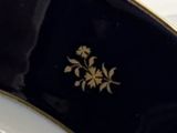 une assiette noire et dorée ornée d'une fleur dorée