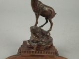 statue d'un cerf posée sur un socle avec une base en bois