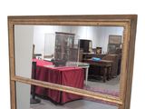 a large mirror with a gold frame and a red table cloth