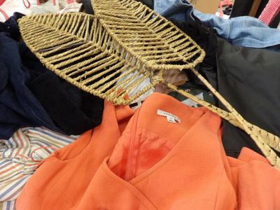 a pile of clothes and a wicker basket on a bed
