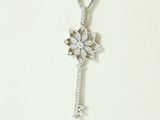 a silver necklace with a diamond key on a chain