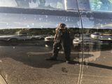 a reflection of a man standing in the reflection of a car