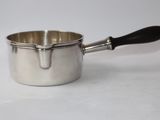 a silver sauce pot with a black handle on a white surface