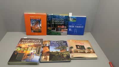 Plusieurs livres sont posés sur une table devant un mur blanc.