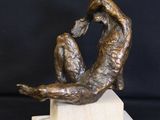 statue of a woman sitting on a marble block with her hands in the air