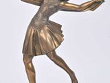 statue en bronze représentant une femme tenant une raquette de tennis, posée sur un socle en bois