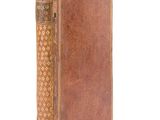an old book with a brown cover sitting on top of a white surface