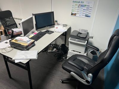 a desk with two computers and a chair next to it