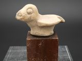 une image représentant un oiseau en pierre posé sur un bloc, sur fond noir