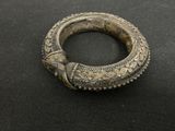 gros plan d'un bracelet en argent sur une surface noire