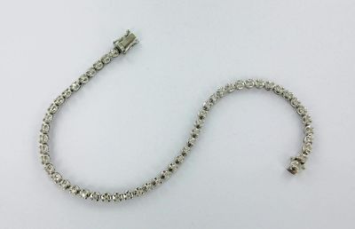 un gros plan d'un bracelet en argent muni d'un fermoir, posé sur une surface blanche