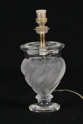 une lampe en verre transparent avec un pied doré sur fond noir