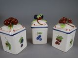 three ceramic containers with fruit painted on them sitting on a table