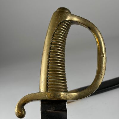 une vieille épée dorée avec une poignée noire sur un fond blanc