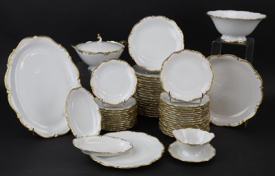 de nombreuses assiettes et bols blancs et dorés sur la table