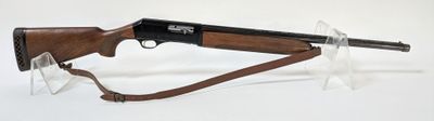 le fusil repose sur un support en verre posé sur une surface blanche