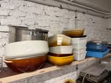 many bowls and pans on a shelf in the kitchen