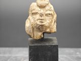 une ancienne tête d'homme sculptée dans la pierre, posée sur un socle
