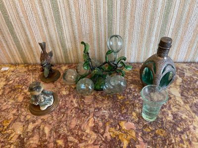 une table sur laquelle se trouvent une bouteille, un vase en verre et d'autres objets