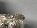 a silver gravy sitting on a table next to a cup
