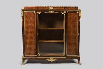 une armoire ancienne en bois, avec des portes vitrées et des garnitures dorées