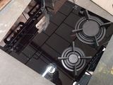 une cuisinière noire posée à même le sol, à côté d'une palette de bois