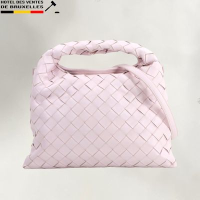 pink leather handbag with woven handle on a white background