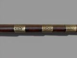 an old wooden stick with gold trimmings on a gray background