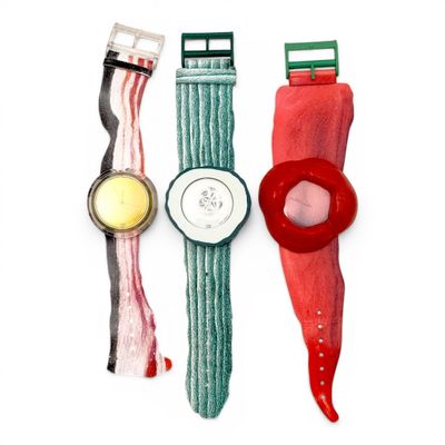 trois montres de couleurs différentes placées l'une à côté de l'autre sur une surface blanche
