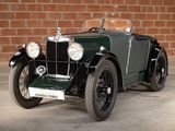 an old green car parked in front of a brick wall
