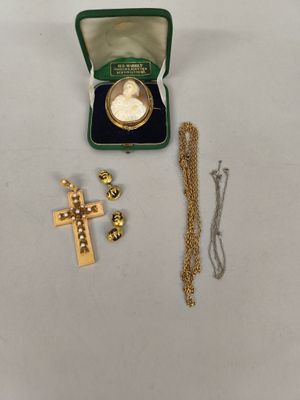 une croix en or et une pièce d'or dans une boîte verte
