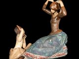 a figurine of a woman sitting on a rock next to a man