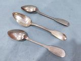 three silver spoons sitting on top of a table next to each other