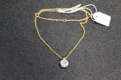 a close up of a gold necklace with a diamond on it