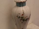 a white vase with a blue lid sitting on a table