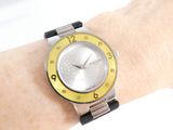 a wrist watch on a woman ' s wrist with a yellow and black band