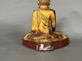 statue of a buddha sitting on a wooden base on a gray background