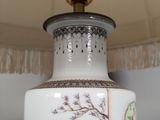 a white vase with a bird on it sitting on a table
