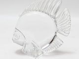 une figurine de poisson en verre posée sur une surface blanche