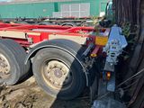 une remorque rouge garée à côté d'un arbre