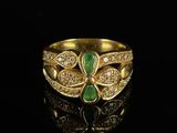 a close up of a gold ring with green and white stones
