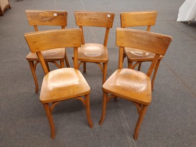 quatre chaises en bois posées les unes à côté des autres par terre