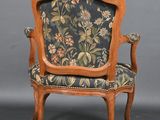 an old chair with a floral upholstered back and a wooden frame
