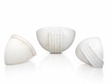 trois vases blancs posés les uns à côté des autres sur une surface blanche